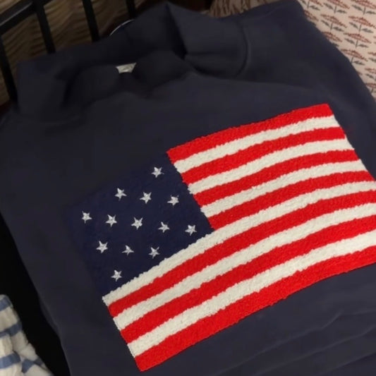 Navy blue sweatshirt with American flag design on a bed