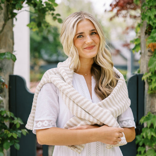 Woman wearing a white dress with a sweater in an outdoor setting