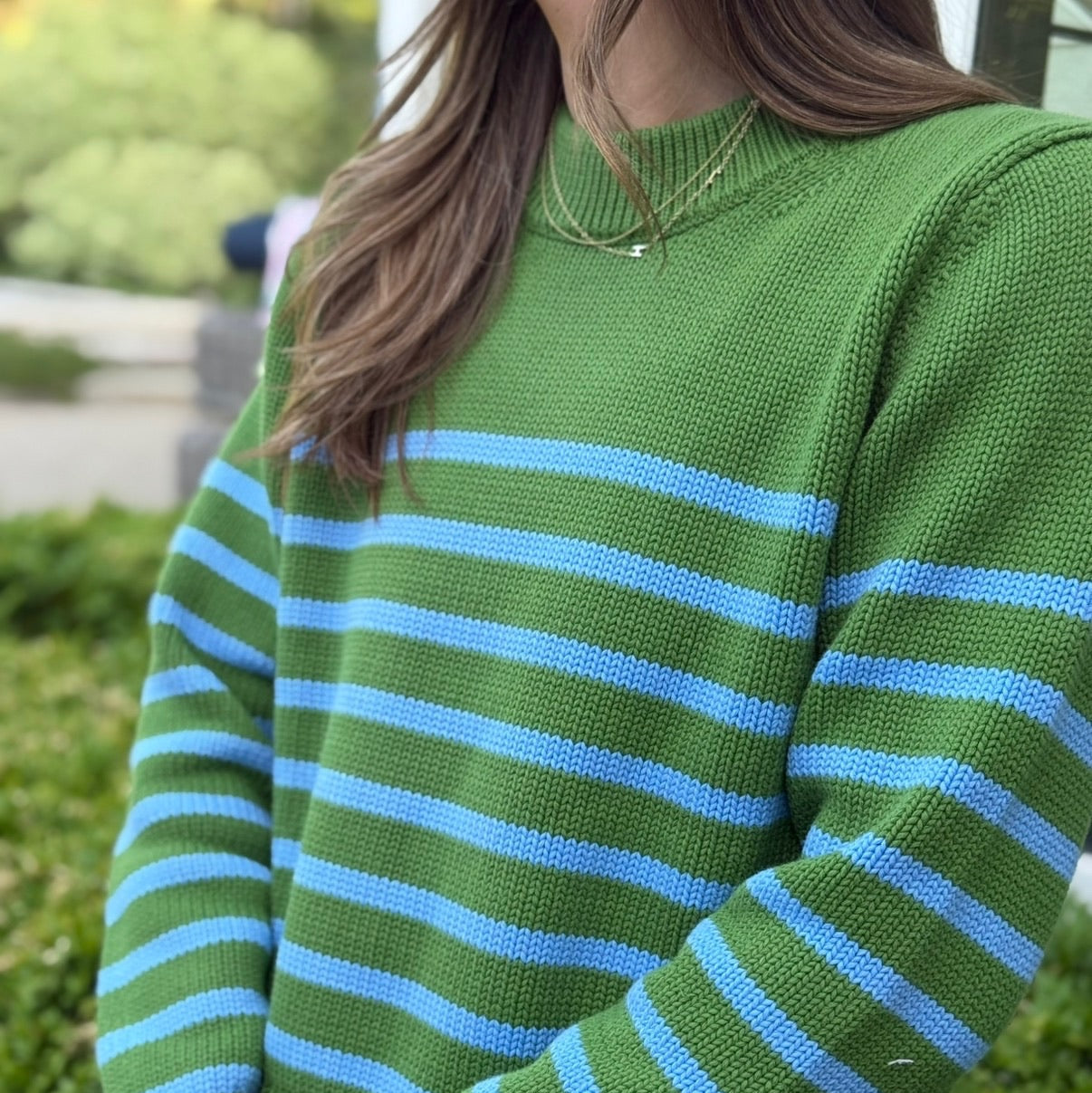 Green sweater with blue stripes worn by a person outdoors