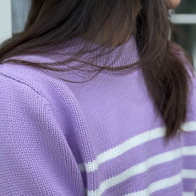 Person wearing a purple sweater with white stripes