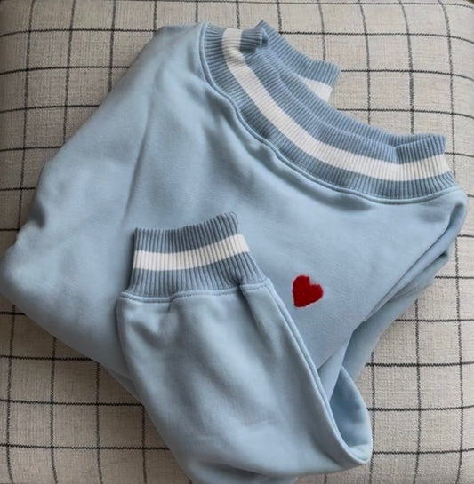 Light blue sweater with white trim and a red heart on a checkered fabric background