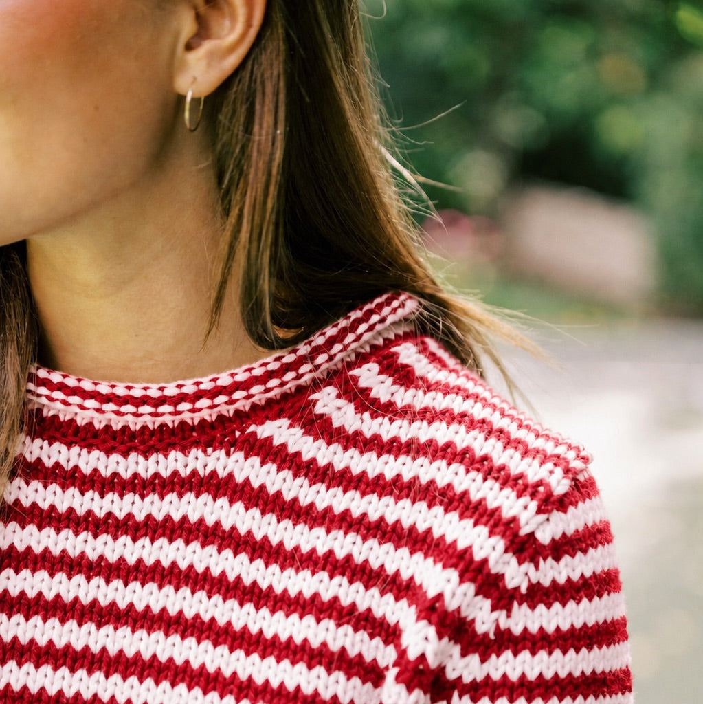 Red and white striped sweater worn by a person with a blurred natural background