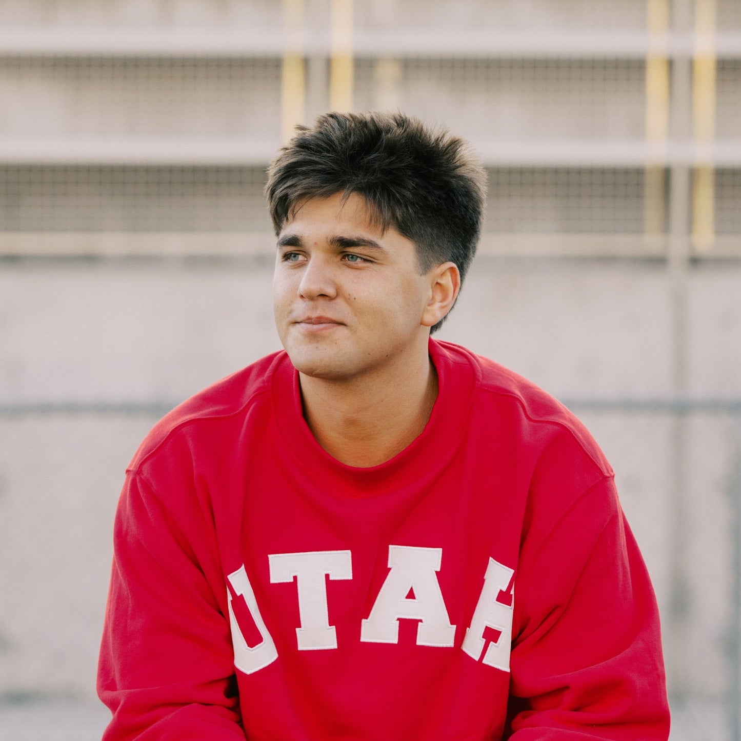 Person wearing a red 'UTAH' sweatshirt sitting on a bench.