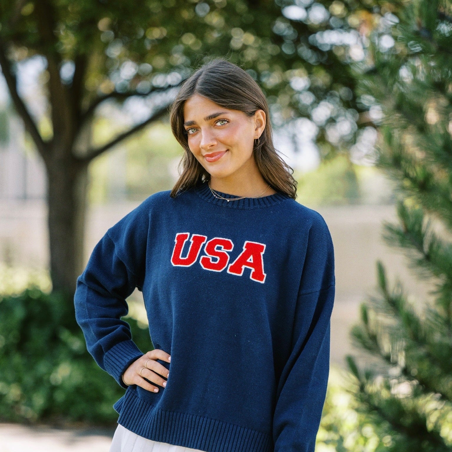 Woman wearing a navy blue sweater with 'USA' printed on it, standing outdoors.