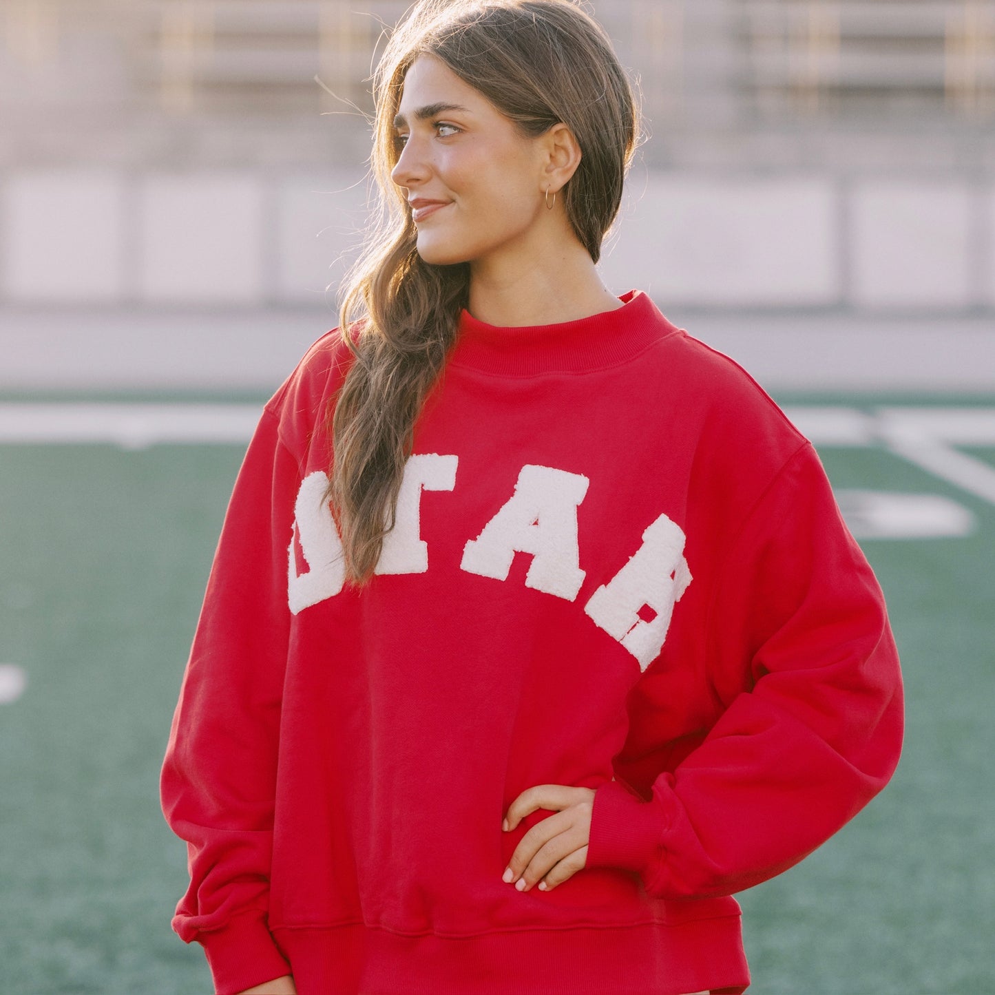 Person wearing a red sweatshirt with 'UTAH' printed on it, standing on a sports field.
