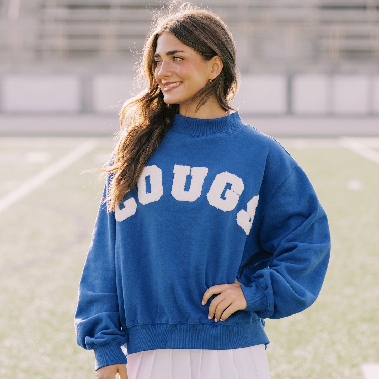 Woman wearing a blue sweatshirt with 'LOUGS' on it, standing outdoors.